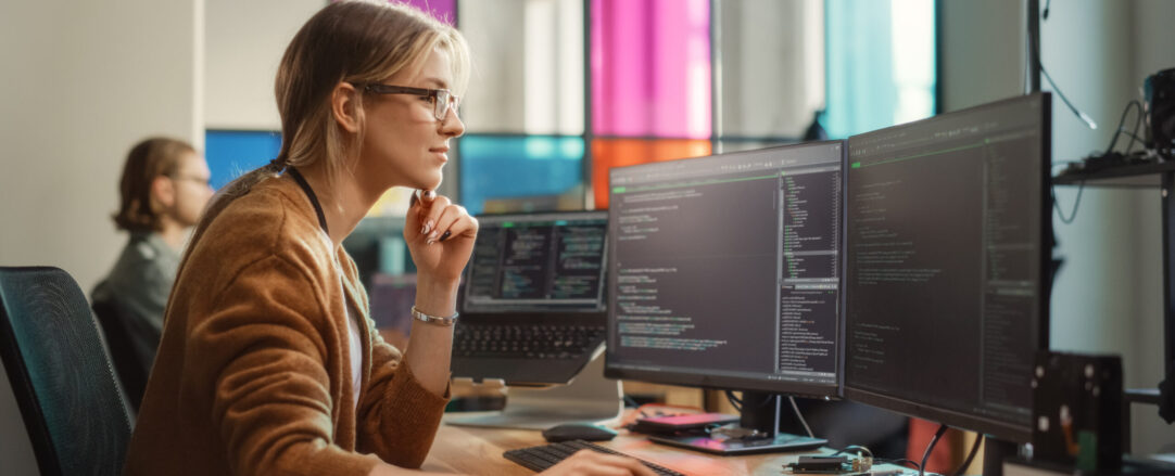 Female Software Engineer Writing Code on Desktop Computer with M