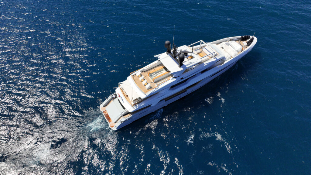 Aerial drone photo of beautiful modern super yacht with wooden deck cruising in low speed deep blue Aegean sea
